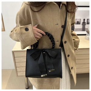 Détail du sac de mariage noir avec un grand nœud en satin et une poignée tressée
