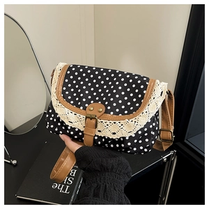 Detail of vintage polka dot crossbody bag with beige lace trim and brown leather strap