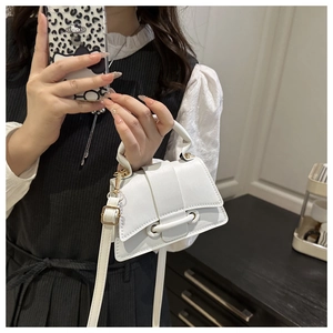 Detail of white mini crossbody bag featuring flap closure and horizontal metal buckle