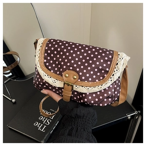 Detail of coffee brown polka dot crossbody bag with lace trim and vintage metal clasp