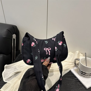 Fashionable black nylon shoulder bag with pink rose and bow prints in casual setting