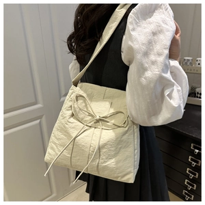Detail view of cream nylon tote bag featuring bow drawstring design and wrinkled texture