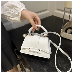 Close-up of white mini handbag featuring gold hardware and a detachable crossbody strap