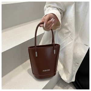 Close-up of brown bucket bag with FASHION logo and metallic hardware detail