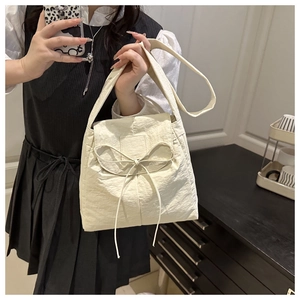 Close-up of beige bow-knot handbag featuring pleated fabric texture for women