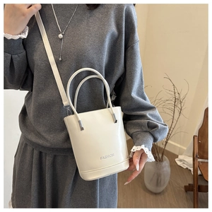Detailed view of a white bucket bag with FASHION text and adjustable shoulder strap