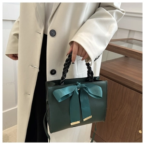 Détail du sac à main de mariée vert foncé avec grand nœud en soie et anses tressées