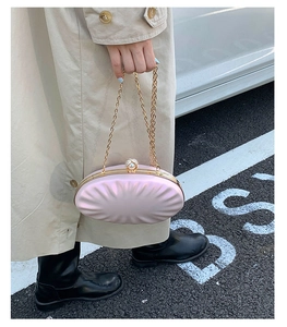 Detail of pink shell evening bag with pearl clasp and golden chain strap