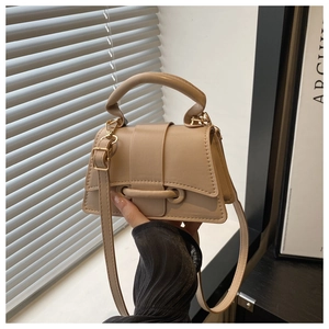 Detail of beige minimalist handbag with golden hardware and adjustable shoulder strap