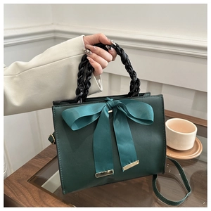 Détail du sac à main carré vert forêt avec un grand nœud en satin et anse tressée