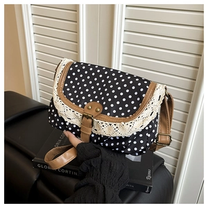 Detailed view of polka dot canvas bag with lace trim and brown leather flap buckle