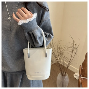 Close-up of white fashion bucket bag with fashion lettering and metallic connectors