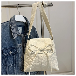 Detail of cream nylon tote bag with delicate bow knot and textured fabric finish