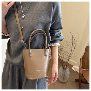 Detail of khaki leather bucket bag with white FASHION lettering and twin top handles