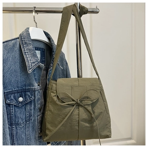Detail view of army green nylon messenger bag featuring a decorative ribbon bow
