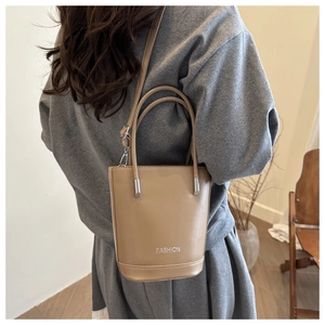 Back view of a khaki bucket bag worn by a model to show product scale and fit