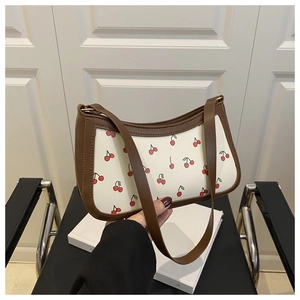 Detail of trendy cherry print underarm bag with brown leather trim and zipper closure