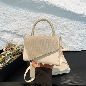 Fashionable cream-colored handbag with sparkling rhinestones and elegant gold trim