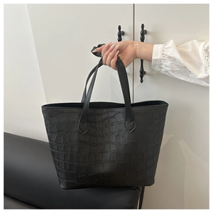 Detail of black crocodile texture on a large tote bag with elegant long handles