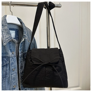Detailed view of black nylon shoulder bag featuring a prominent decorative fabric bow tie
