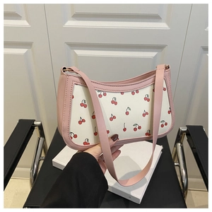 Detailed close-up of a pink leather shoulder bag with vibrant red cherry print accents