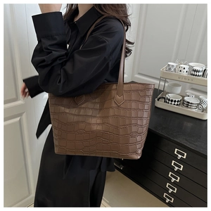 Close-up of deep brown tote bag featuring luxury crocodile texture and slim shoulder straps