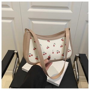 Detail of cream shoulder bag with red cherry print and beige leather handle strap