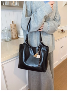 Detail of black glossy tote bag with FASHION text and baseball glove charm accessory