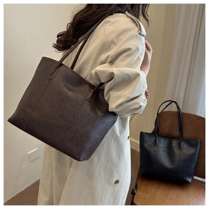 Dettaglio macro della borsa tote in pelle marrone scuro con scritte oro e grana naturale