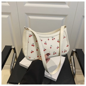 Detail of retro cream underarm bag featuring vibrant red cherry prints and metallic zipper