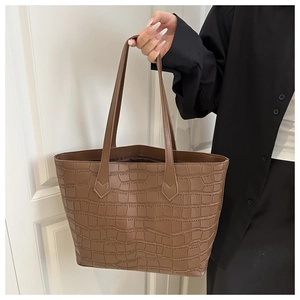 Detail of brown tote bag featuring crocodile pattern texture and long shoulder strap
