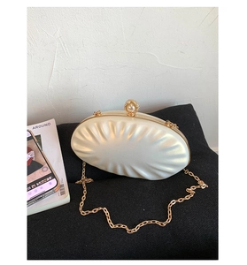 Close-up of shell-shaped pearl evening clutch with gold frame and detachable chain