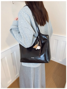 Close-up of black glossy tote bag with FASHION logo and creative sports charms