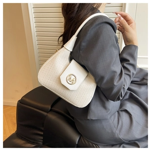 Detail shot of white crocodile-embossed leather bag with gold metal M logo and strap