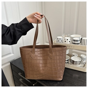 Brown crocodile embossed tote bag held by hand to show large capacity and commuter style