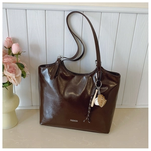 Detail of dark coffee tote bag in glossy leather with silver buckles and fashion logo