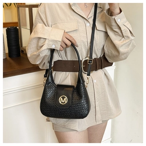 Close-up of black woven texture handbag featuring a distinctive gold M-shaped metal clasp