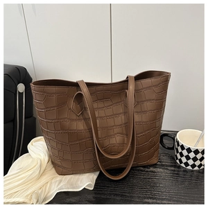 Close-up of brown crocodile pattern tote bag with dual straps on a wooden table