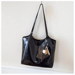 Detail of black glossy leather tote bag with adjustable silver buckle and fashion logo