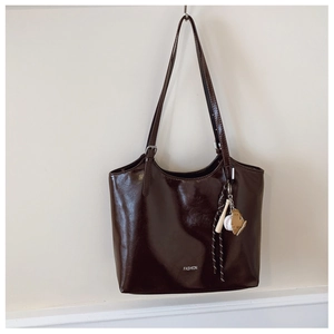 Close-up of brown patent leather tote bag with glossy finish and fashion lettering