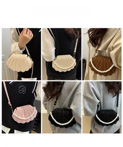 Detail view of shell-shaped crossbody bags featuring large pearl top handles and pleated texture