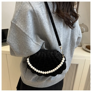 Detail of shell-shaped velvet bag with elegant white pearl chain on model's shoulder
