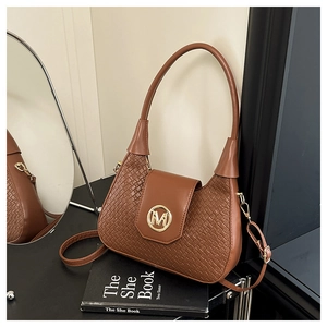 Détail d'un sac sous le bras en cuir tressé marron avec logo M doré et boucles en métal