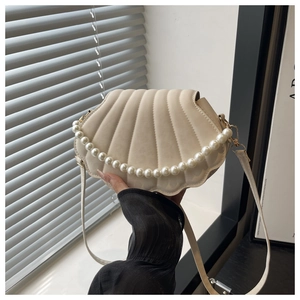 Detail of shell-shaped crossbody bag with pearl chain handle and leather strap