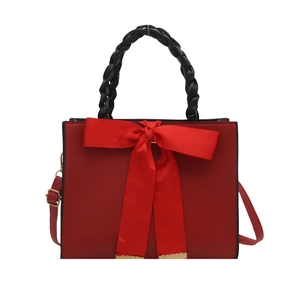 Sac à main de mariée rouge élégant avec nœud et poignée tressée noire sur fond blanc