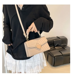 Detail of the quilted chevron pattern and pleated handle on the beige crossbody bag