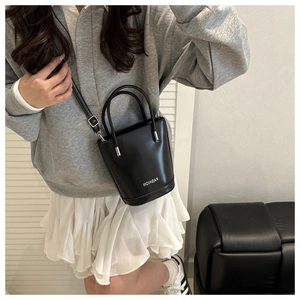 Detail of black leather bucket bag showing silver hardware and fashion text embroidery
