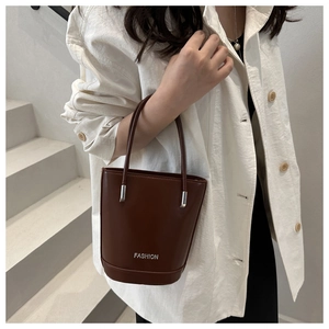 Detail of a brown leather bucket bag with silver buckle and white FASHION logo text