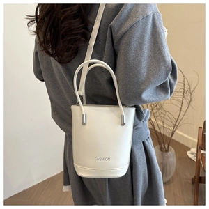Close-up of white leather bucket bag with silver metal handle and fashion print detail