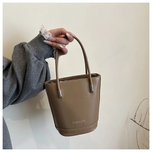 Detail of tan bucket bag showing the silver Fashion letter print and premium texture